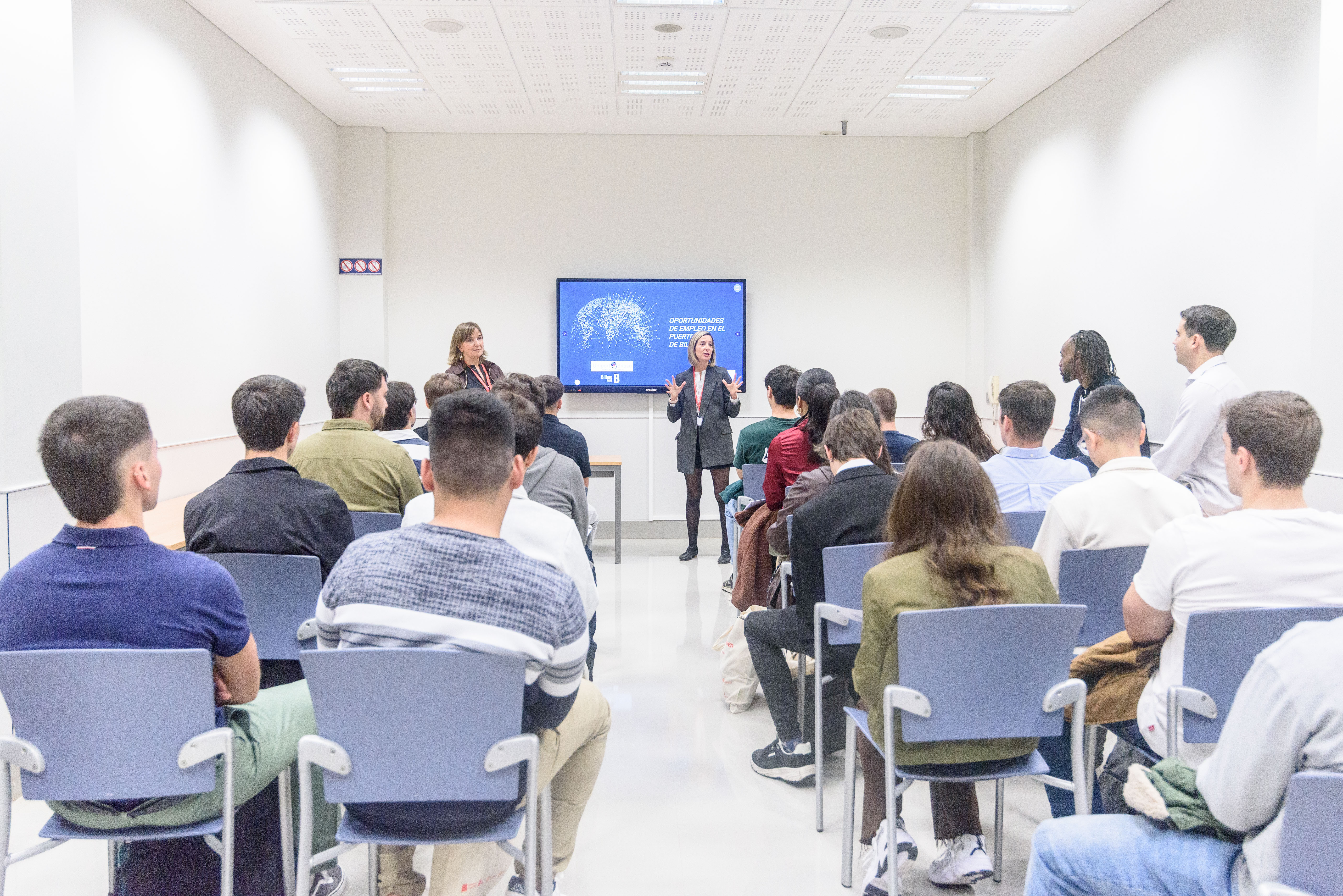 Mujer en sala impartiendo una charla a jovenes